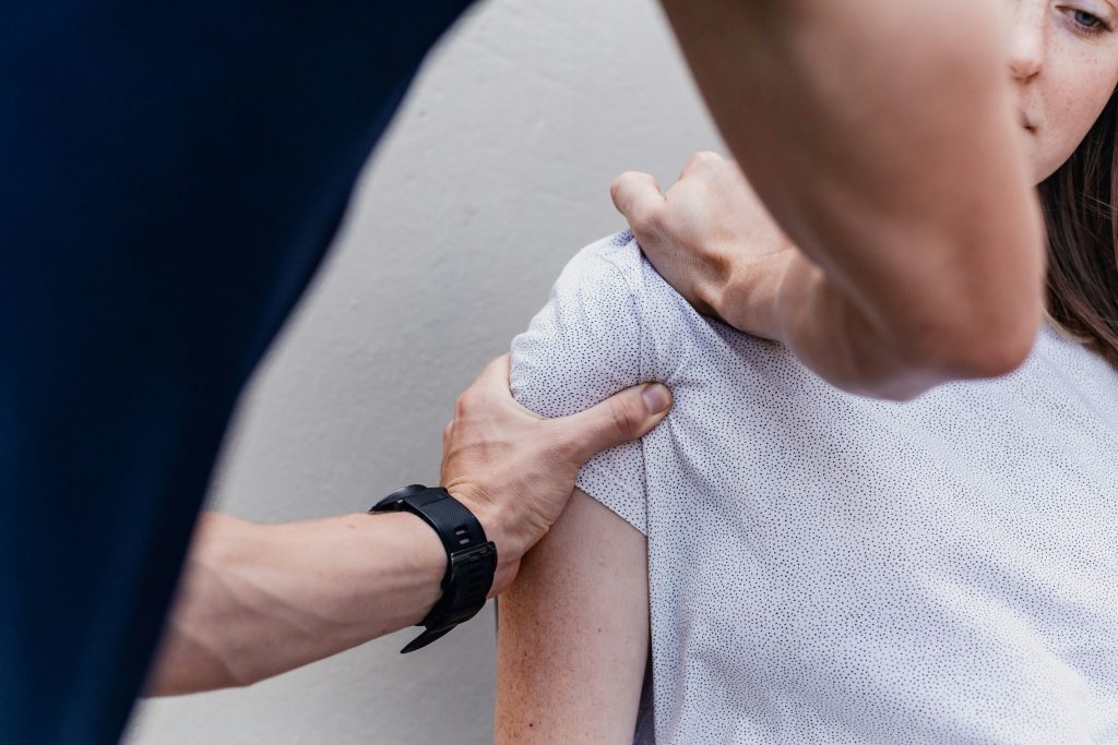 Our healthcare professional's hands applying targeted pressure to a patient's shoulder and neck area during a treatment session.